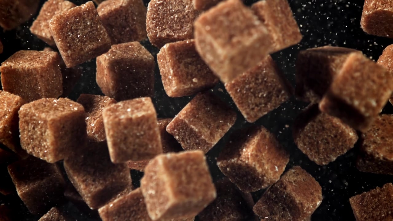 Brown Sugar Cubes Falling in Slow Motion on Black Background