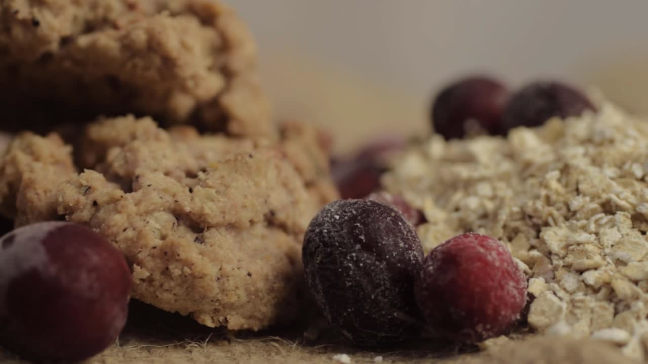 Dry rolled oats with cranberries and cookies panning close up shot