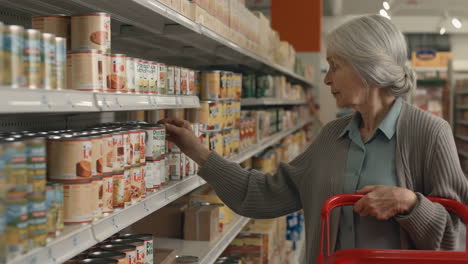 elderly woman shopping for canned goods in a grocery store aisle