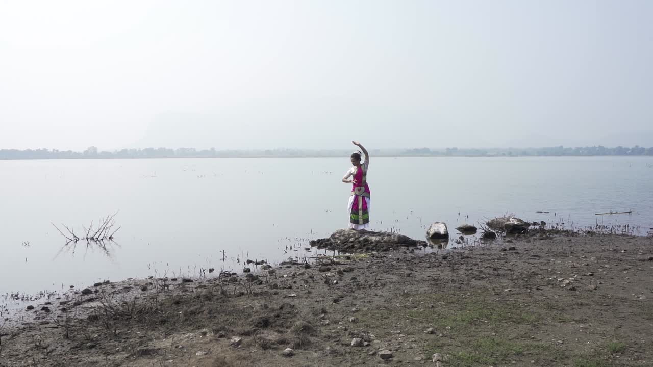una bailarina de bharatnatyam que muestra una pose clásica de bharatnatyam en la naturaleza del lago vadatalav, pavagadh
