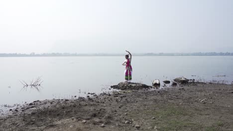 Una-Bailarina-De-Bharatnatyam-Que-Muestra-Una-Pose-Clásica-De-Bharatnatyam-En-La-Naturaleza-Del-Lago-Vadatalav,-Pavagadh