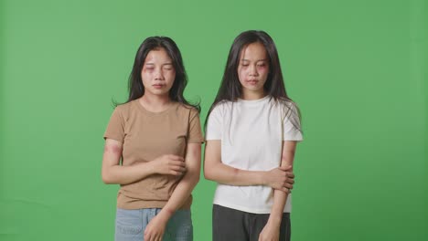 young asian women victims of violence touching bruises on their bodies that caused from physically abused in the green screen background studio