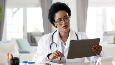 african american female doctor in a white lab coat reviews a tablet on video call consultation