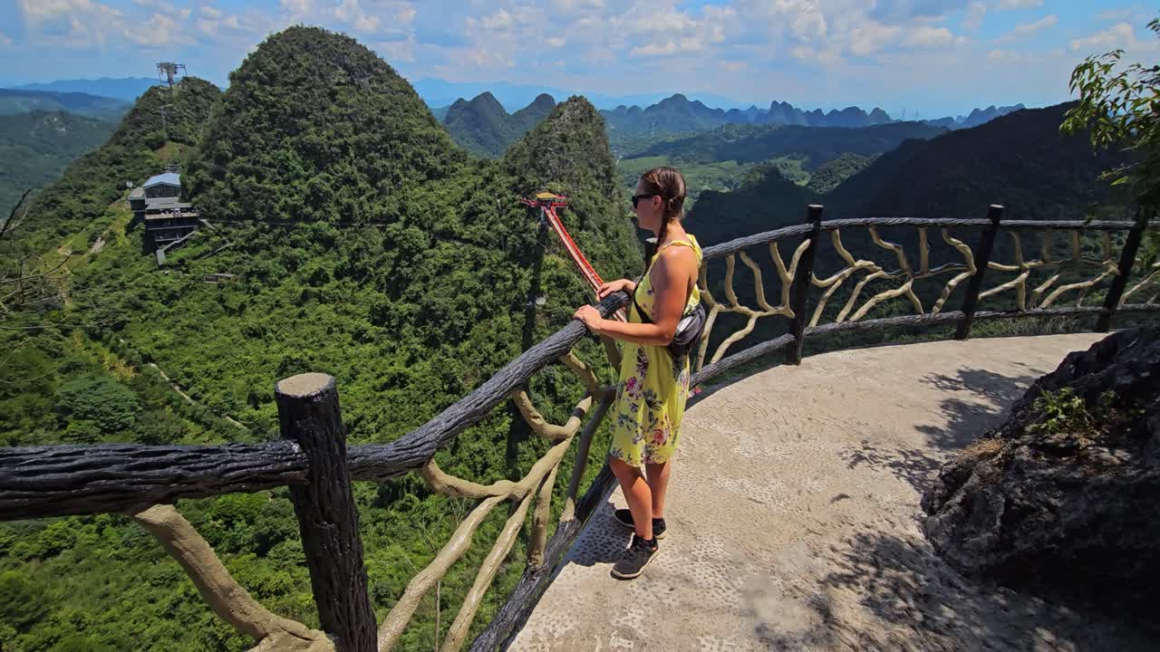 Woman standing at a fence admiring the view from Ruyi Peak, summer in China