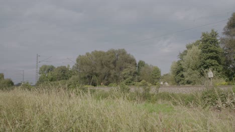 Red-train-speeding-through-countryside,-overcast-sky,-motion-blur-effect