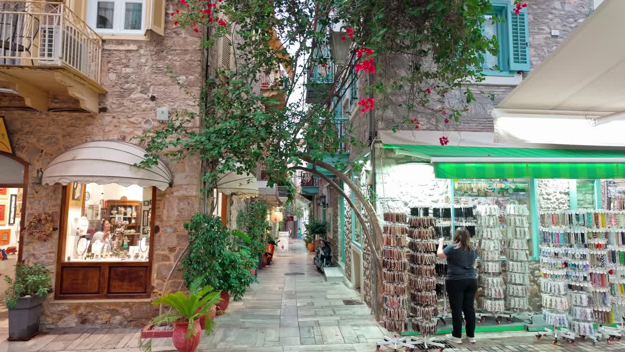 Boutique Souvenir shops on pretty floral Greek paved street ,evening