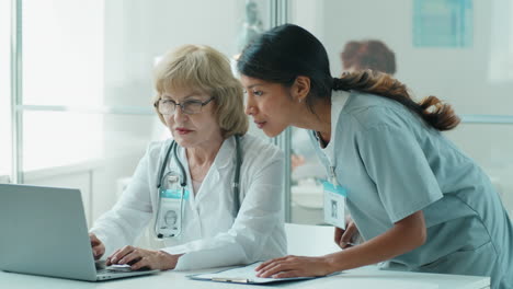 Hispanic-Nurse-and-Senior-Caucasian-Doctor-Using-Laptop-and-Speaking