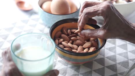 elderly person eating almonds and milk