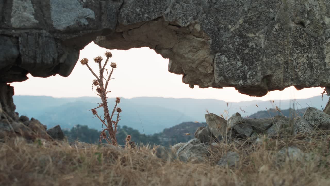 a través de un agujero en las ruinas de un viejo muro de piedra, se puede ver la cordillera del sur de italia.