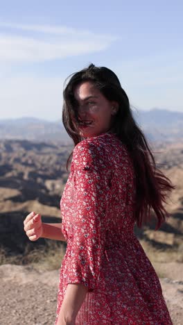 woman in a red floral dress posing in a scenic outdoor landscape