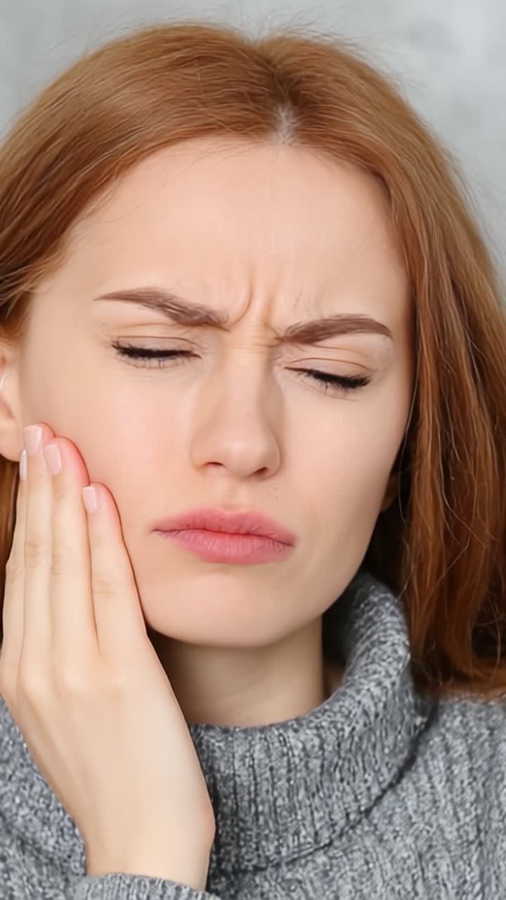 Woman Gripping Her Cheek in Pain: An Expression of Discomfort and Distress with a Focus on Toothache and Facial Discomfort in a Neutral Setting