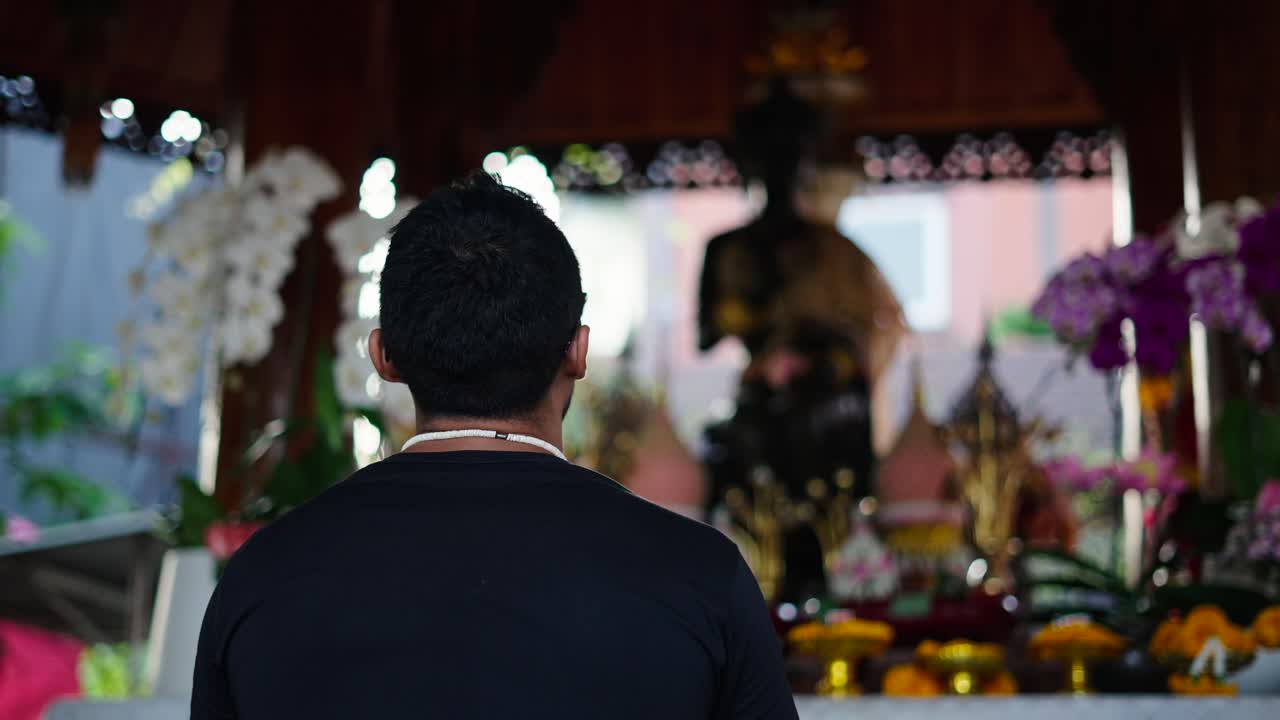 Persona che prega in un tempio thailandese