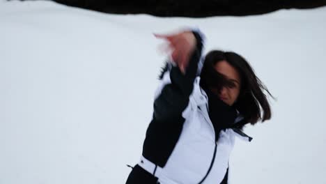 playful woman wear winter parka and throw snowball, bright snowy background