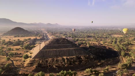 drone footage over pyramid with hot air balloon on the back at the morning