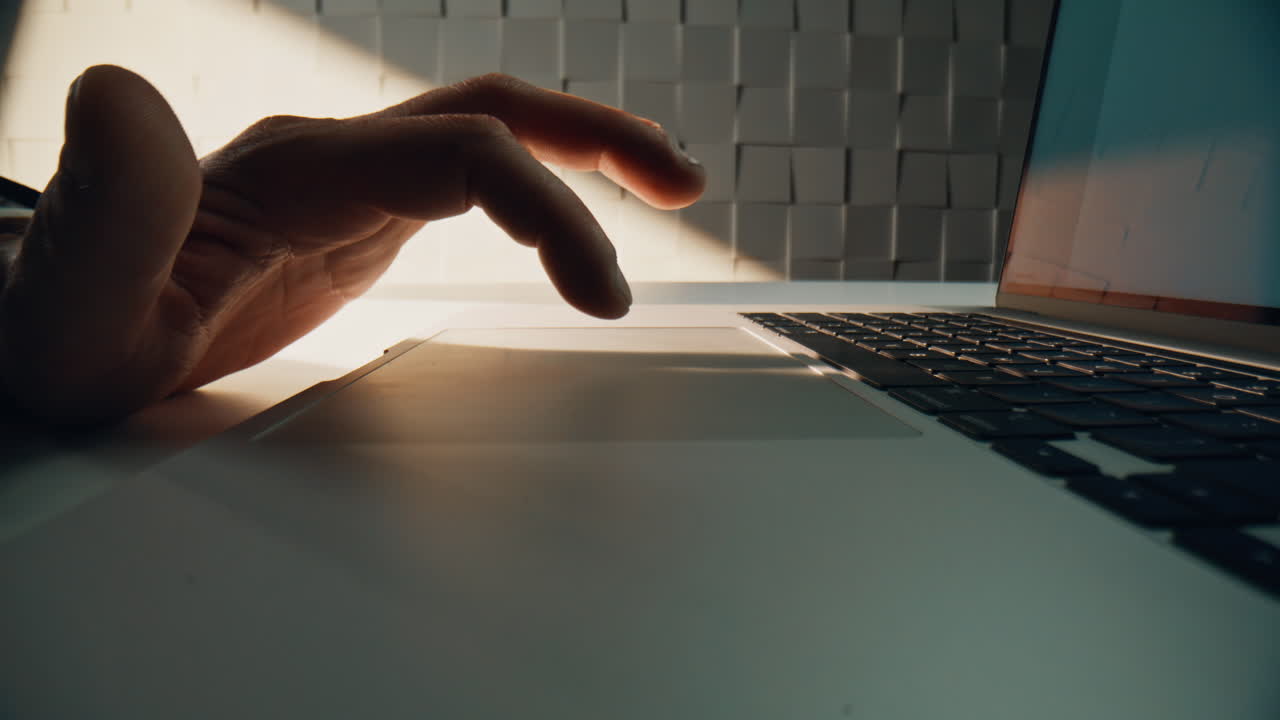 Macro fingers swiping touchpad laptop in office environment. Freelancer working