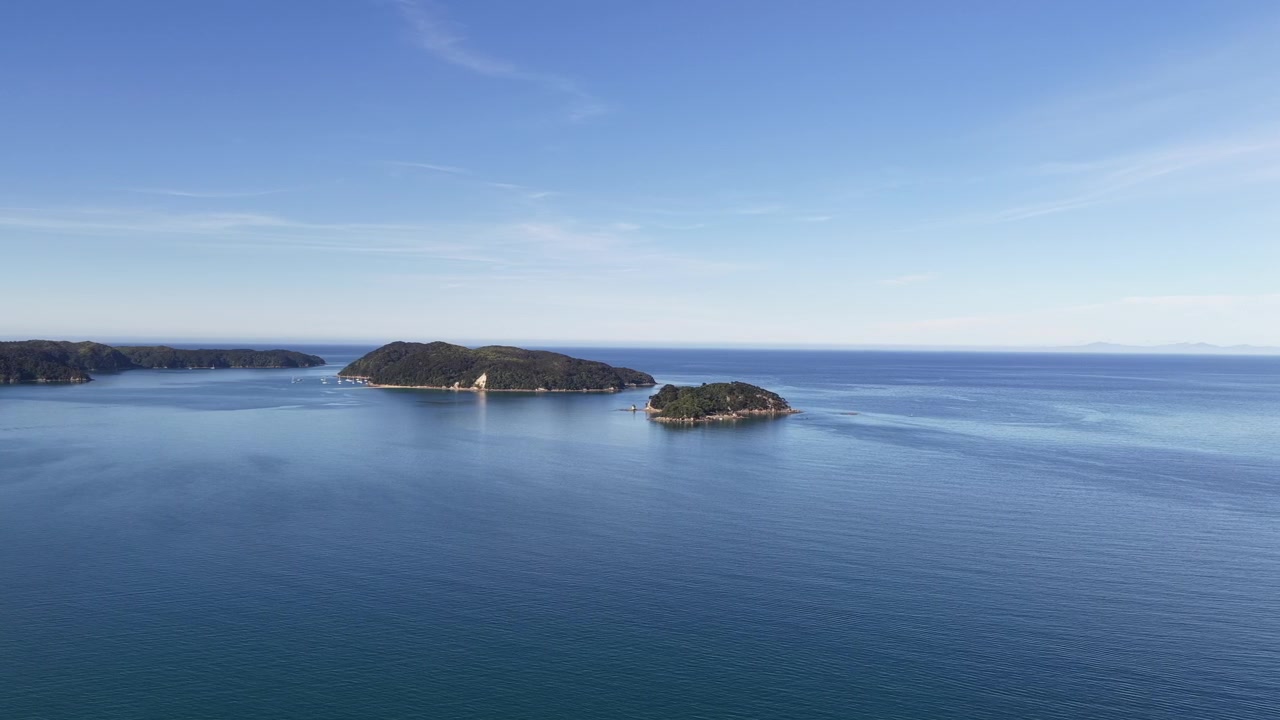 Filmisk droneudsigt over roligt hav og fjerntliggende øer nær New Zealands Sydø, afslapning og natursyn.