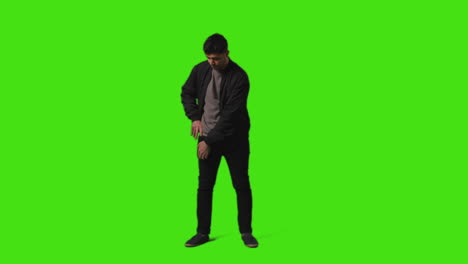 Young-Man-Getting-Alert-And-Looking-At-Text-Message-On-Mobile-Phone-Standing-Against-Green-Screen-3