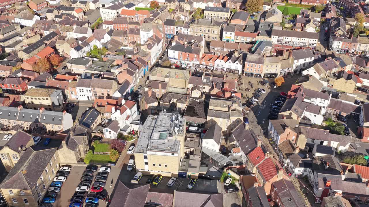 Top down aerial view of dense rooftops, winding streets and tightly packed residential and commercial buildings in central Knaresborough, North Yorkshire, England with parking lots visible