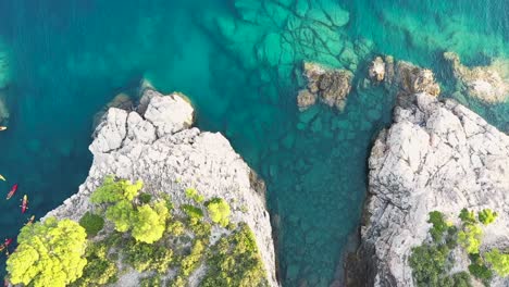 Aufsteigende-Luftaufnahme-Einer-Gruppe-Von-Touristen-Auf-Kajaks,-Die-An-Der-Insel-Lokrum-In-Der-Nähe-Von-Dubrovnik-An-Der-Adriaküste-Kroatiens-Vorbeifahren