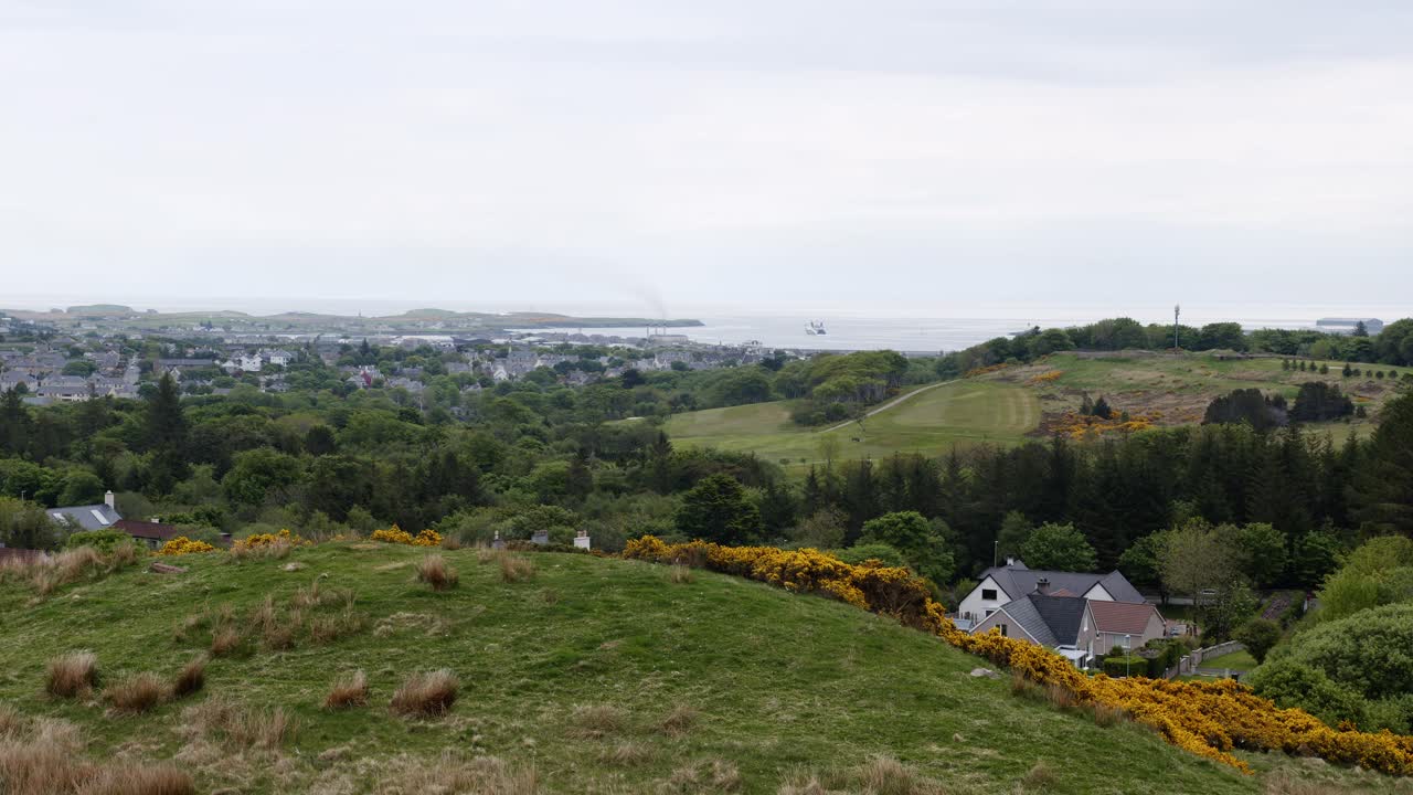 Wide shot of the small, port village of Stornoway and the houses and landscape surrounding it