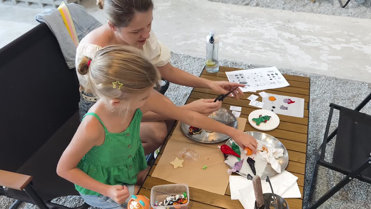 어머니 와 딸 이 함께 쿠키 를 장식 하고 있다