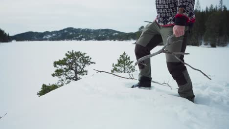 person dig a small hole and putting some dried tree branches for campfire