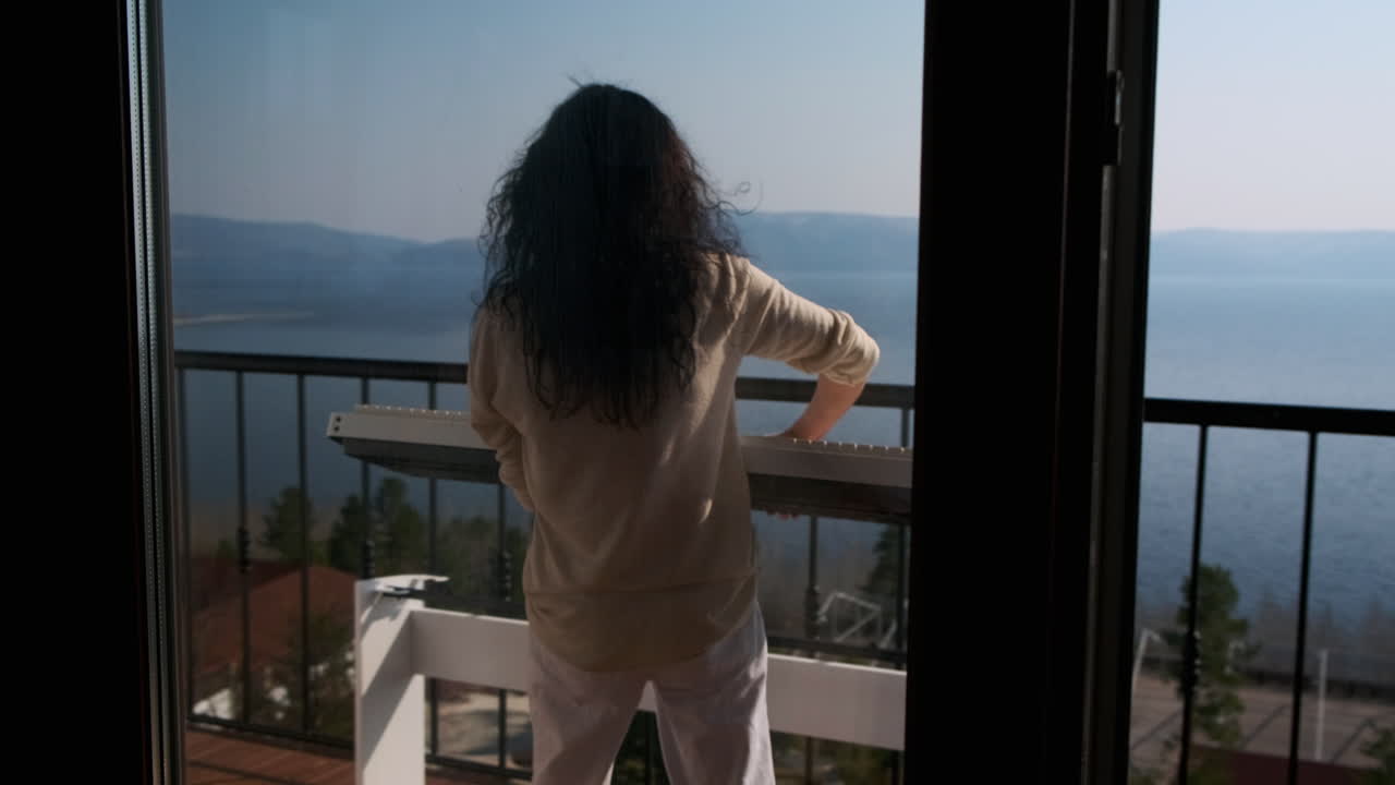 Donna che suona il pianoforte su un balcone con vista lago