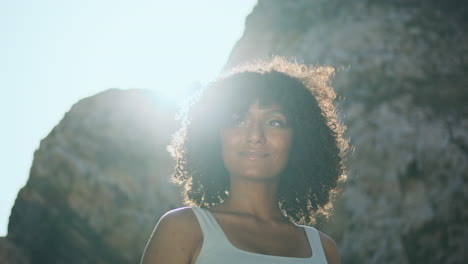 Mujer-Africana-Sonriente-De-Pie-En-La-Playa-Iluminada-Por-La-Luz-Del-Sol-Vista-Vertical-De-Cerca