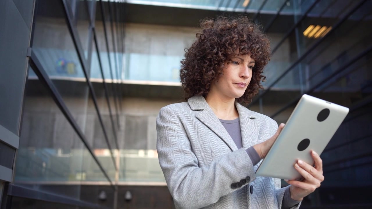Una donna professionista che usa abilmente un tablet in un ambiente urbano all'avanguardia oggi.
