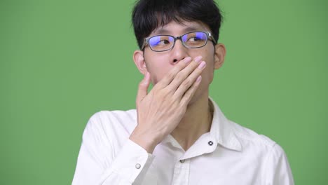 young asian businessman covering mouth and looking guilty