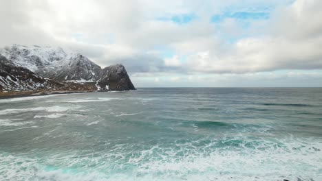 aerial view pan of ocean waves and snowy mountains, lofoten, norway