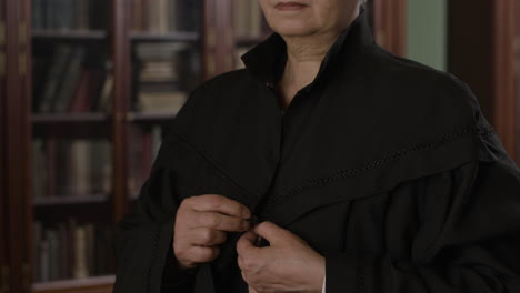 older woman in formal robe in a library