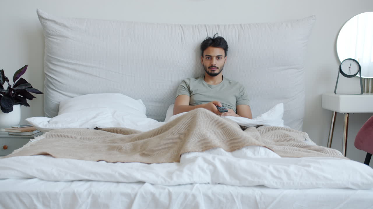 Man Relaxing in Bed with Remote