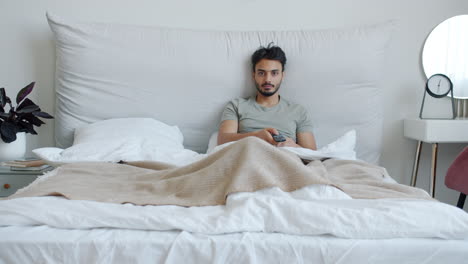 man relaxing in bed with remote
