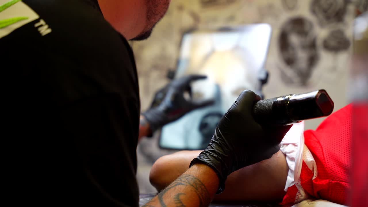 Shift focus shot of a tattoo dog design and the artist working on it with precision