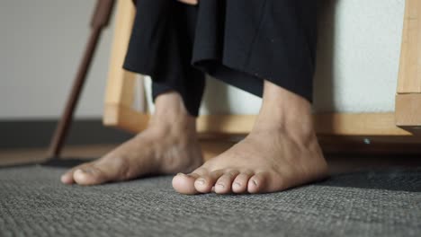 close up of bare feet of a person sitting on a wooden chair