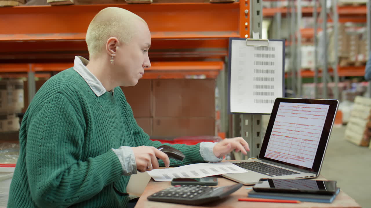 Donna che usa scanner e laptop al lavoro in magazzino.