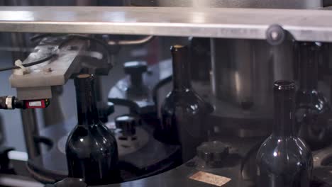 línea de producción de vino: botellas de vino sin etiquetar que se mueven en una cinta transportadora en una máquina embotelladora de vino