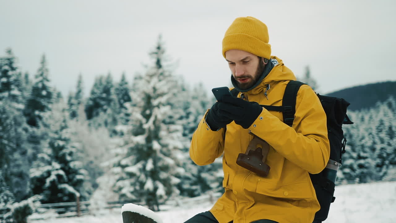 Uomo che usa il cellulare in una foresta innevata in inverno