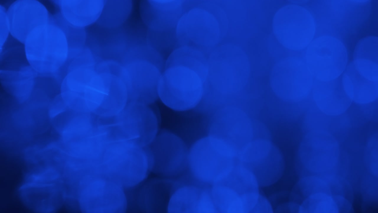 Reflection of blurry blue lights in the water. Wave, ripples and bokeh of blue lights.