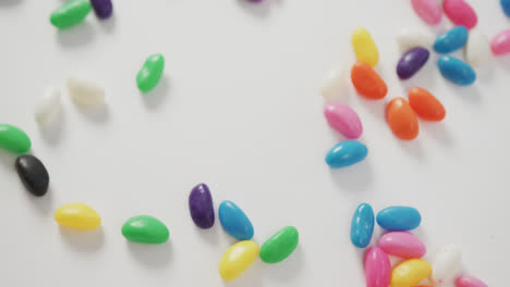 video of close up of multi coloured sweets spinning over white background