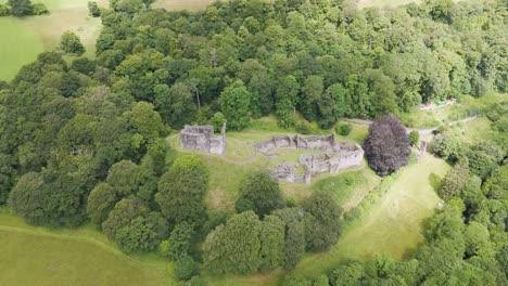 Drone-orbital-of-Okehampton-Castle-amidst-dense-greenery-in-Devon,-UK