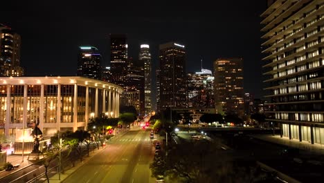 Toma-Aérea-Lenta-Al-Lado-De-La-Gran-Avenida-Por-La-Noche-Con-El-Pabellón-Dorothy-Chandler-Iluminado-Por-La-Noche