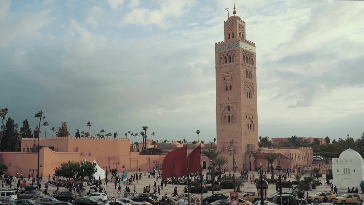 Hyperlapse view of Marrakesh old town featuring the Koutoubia Mosque minaret, busy square with people and traffic, historic architecture, and vibrant city atmosphere