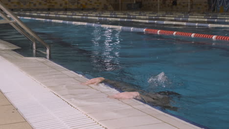 A-Young-Female-Swimmer-With-Cap-And-Goggles-Leaves-The-Pool-After-A-Swimming-Session