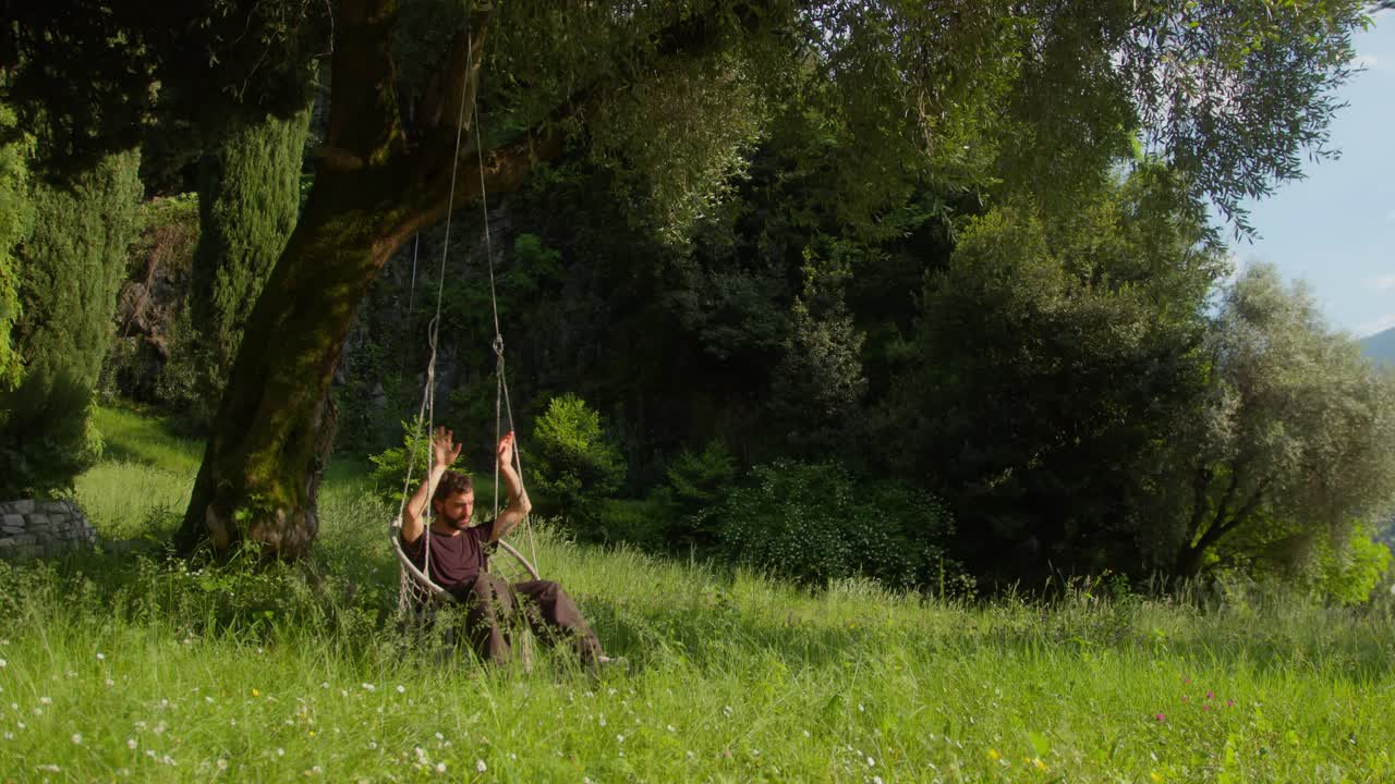 Close-up of man alone on hanging bench at sunset in Lake Como, Italy (Lago di Como, Italia), reflecting in peace