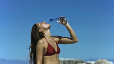 una morena bebiendo agua en cámara lenta.