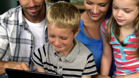 Glückliche-Familie-Sitzt-Auf-Einem-Sofa-Und-Schaut-Gemeinsam-Auf-Ein-Tablet