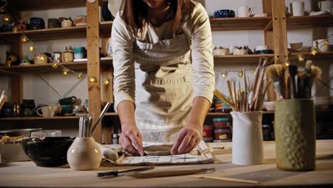 young woman potter putting the clay in a smooth circle shape