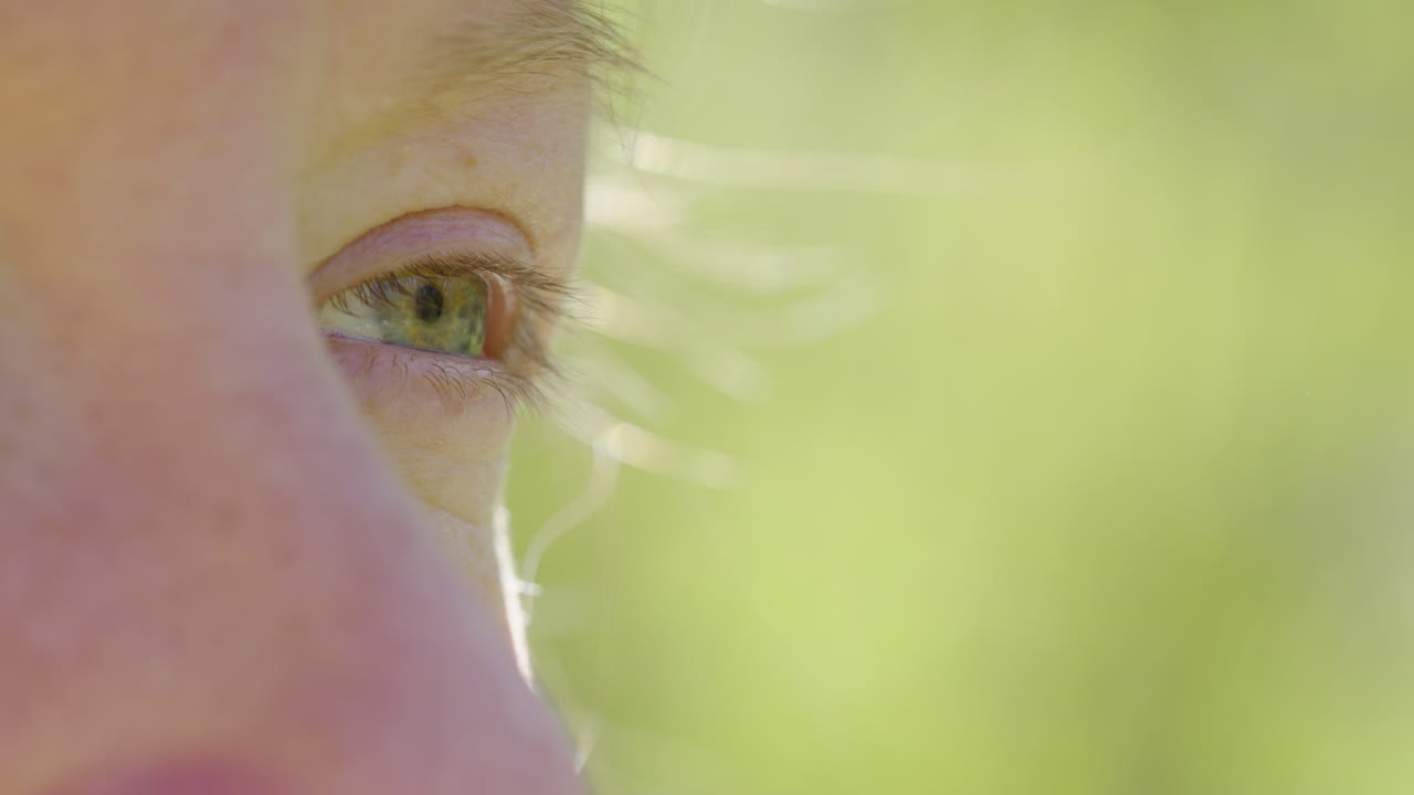 Woman closes eye as hair flutters in breeze during spiritual meditation outdoors